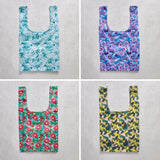Four floral-patterned reusable shopper bags on a concrete surface